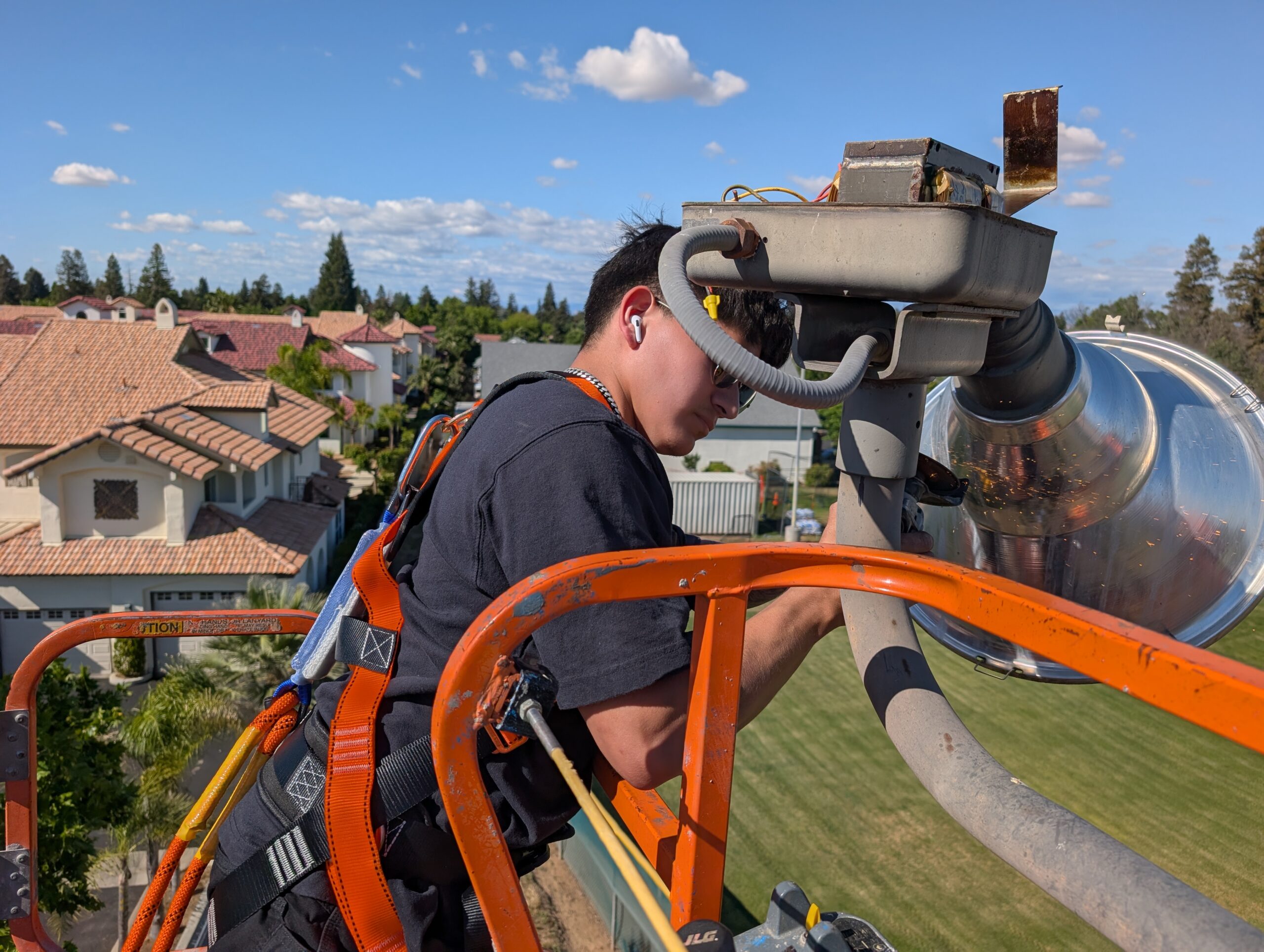 Technician installing new LED sports light from JLG boom lift
